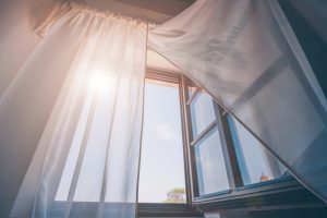 Ljus morgonsol i det öppna fönstret genom gardinerna